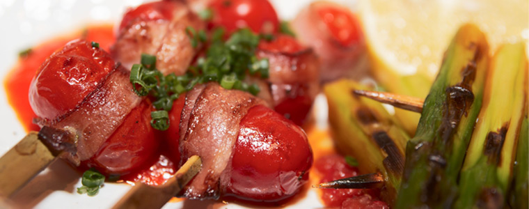 Plato con tomates, tocino y espárragos en un catering