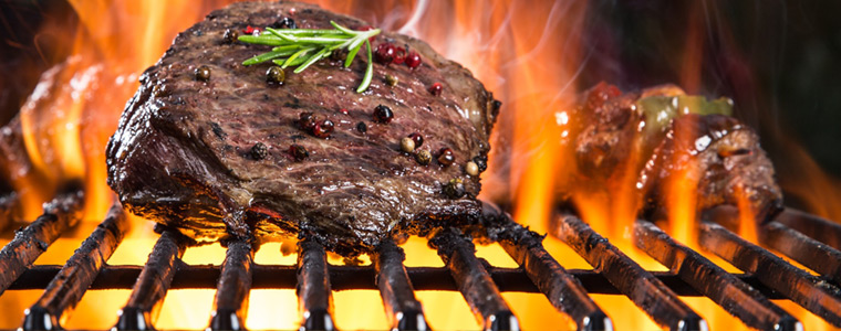 Filetes de carne en la parrilla con llamas y humo