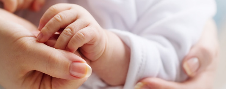 Bautizo con mano de bebé en las manos de su madre