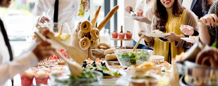 Personas comiendo de buffet en celebración de la empresa