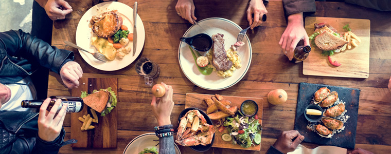 Diversas personas cenando en mesa de madera