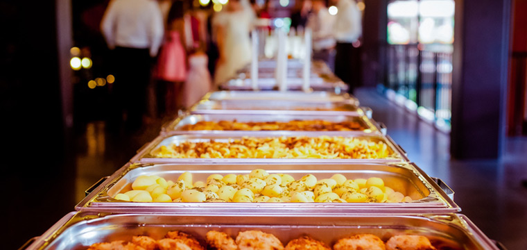 Mesa de catering repleta de bandejas de alimentos en bufet
